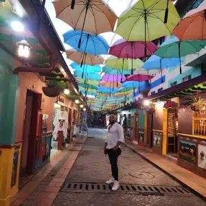 Colorful umbrella street in Guatapé Colombia at night with cobblestone alley and painted buildings