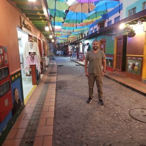Colorful umbrella street in Guatapé Colombia at night with cobblestone alley and painted buildings