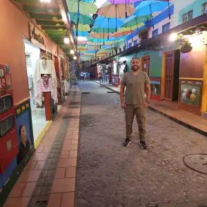 Colorful umbrella street in Guatapé Colombia at night with cobblestone alley and painted buildings
