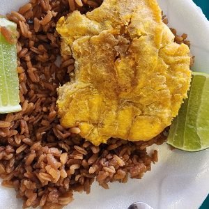 Patacon fried green plantain traditional street food in Medellin served with arroz con coco and lime